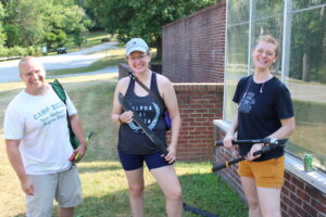 Three people standing in front of greenhouse 